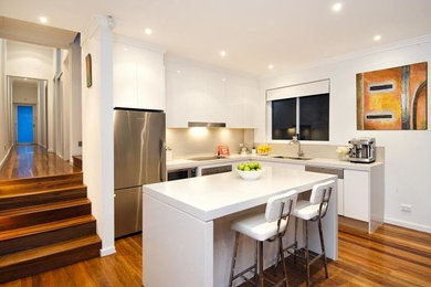 Design ideas for a small contemporary l-shaped open plan kitchen in Sydney with a double-bowl sink, open cabinets, white cabinets, solid surface benchtops, beige splashback, porcelain splashback, white appliances, painted wood floors, with island, multi-coloured floor and white benchtop.