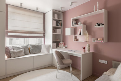 Modelo de habitación de niña de 4 a 10 años actual de tamaño medio con escritorio, paredes rosas, suelo laminado y suelo beige