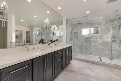 Mid-sized minimalist master gray tile double-sink bathroom photo in Orange County with raised-panel cabinets, dark wood cabinets, a one-piece toilet, white walls, quartzite countertops, a hinged shower door, white countertops and a built-in vanity
