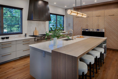 Open concept kitchen - large contemporary l-shaped medium tone wood floor open concept kitchen idea in Denver with an undermount sink, flat-panel cabinets, quartzite countertops, paneled appliances and an island
