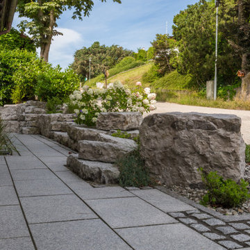 Grüner Steingarten mit individueller Treppe in Hanglage