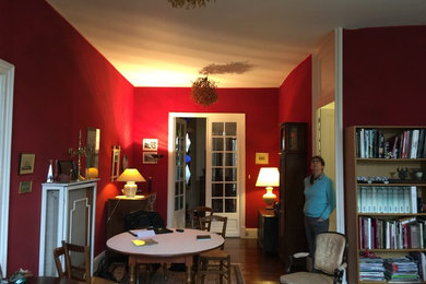 Aménagement d'un salon de taille moyenne et fermé avec une bibliothèque ou un coin lecture, un mur rouge, un sol en bois brun et un sol marron.