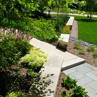 Large contemporary front yard garden in Milwaukee with natural stone pavers and a retaining wall.