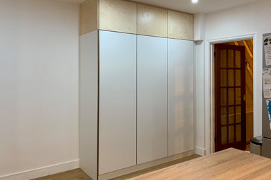 Immagine di una cucina moderna di medie dimensioni con ante lisce, ante bianche, top in laminato e pavimento in legno massello medio