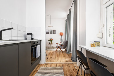 This is an example of a mid-sized scandinavian kitchen in Berlin with painted wood floors and brown floor.