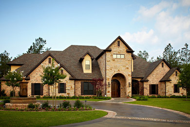 Example of a large arts and crafts beige two-story mixed siding house exterior design in New Orleans with a hip roof and a shingle roof