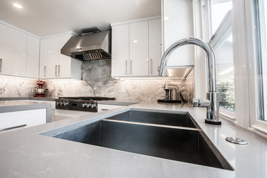 Inspiration for a large contemporary u-shaped medium tone wood floor kitchen remodel in Orange County with a double-bowl sink, flat-panel cabinets, white cabinets, quartz countertops, stone tile backsplash, stainless steel appliances and an island