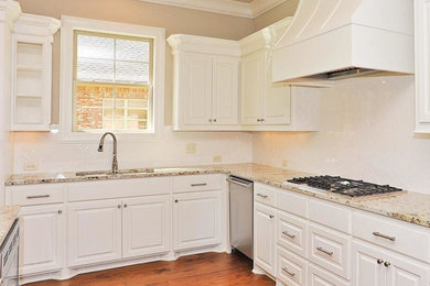 Inspiration for a mid-sized transitional l-shaped dark wood floor and brown floor open concept kitchen remodel in Jackson with a double-bowl sink, raised-panel cabinets, white cabinets, granite countertops, white backsplash, ceramic backsplash, stainless steel appliances and an island