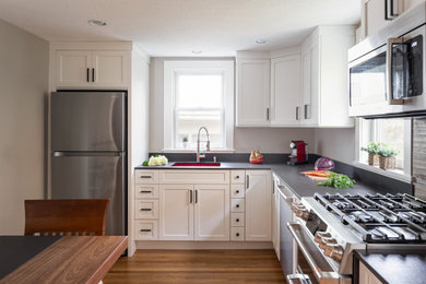 Inspiration for a mid-sized transitional l-shaped light wood floor and brown floor eat-in kitchen remodel in Boston with an undermount sink, flat-panel cabinets, white cabinets, quartz countertops, gray backsplash, porcelain backsplash, stainless steel appliances, an island and gray countertops