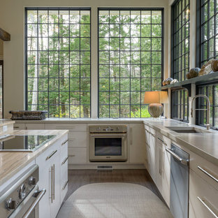 Réalisation d'une cuisine tradition en L avec un placard à porte plane et des portes de placard beiges.