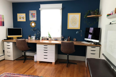 Example of an eclectic built-in desk medium tone wood floor and brown floor home office design in Boston with blue walls