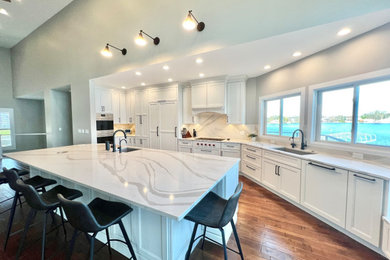 Inspiration for a huge contemporary l-shaped dark wood floor and vaulted ceiling eat-in kitchen remodel in Detroit with shaker cabinets, white cabinets, granite countertops, granite backsplash, stainless steel appliances and an island