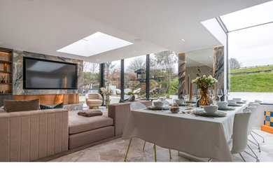 Large modern formal and grey and brown enclosed living room in London with multi-coloured walls, carpet, a standard fireplace, a concrete fireplace surround, a built-in media unit, beige floors, a wood ceiling, brick walls and feature lighting.