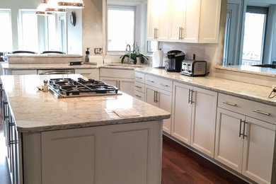 Example of a large trendy eat-in kitchen design in Cedar Rapids with a farmhouse sink, flat-panel cabinets, white cabinets, granite countertops, multicolored backsplash, stainless steel appliances and an island