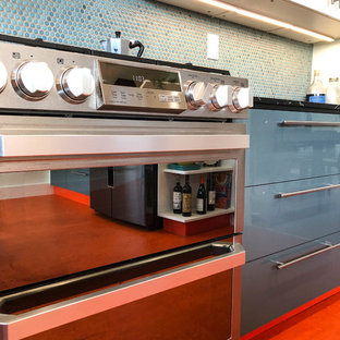 Inspiration för ett mellanstort funkis svart svart kök, med släta luckor, vita skåp, blått stänkskydd, rostfria vitvaror, linoleumgolv, en halv köksö, orange golv, en nedsänkt diskho, granitbänkskiva och stänkskydd i mosaik