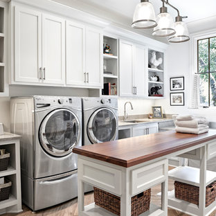 ナッシュビルの大きいトランジショナルスタイルのおしゃれな家事室 (シングルシンク、シェーカースタイル扉のキャビネット、白いキャビネット、ライムストーンカウンター、白い壁、スレートの床、左右配置の洗濯機・乾燥機) の写真