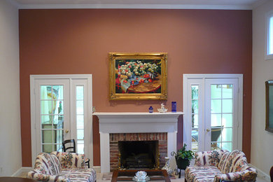 Example of a large carpeted living room design in New York with brown walls, a standard fireplace, a brick fireplace and no tv