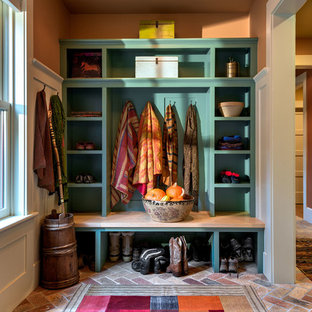 Idee per un ingresso con anticamera country con pareti arancioni, pavimento in mattoni e una porta in legno scuro