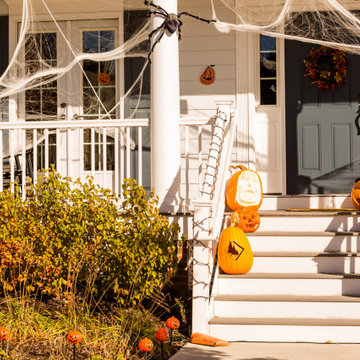 Spooky Fall Decorated Entryway of a Traditional Home with a Bold Door and Column