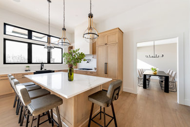 Huge minimalist l-shaped medium tone wood floor and brown floor open concept kitchen photo in Other with a farmhouse sink, shaker cabinets, light wood cabinets, quartz countertops, white backsplash, porcelain backsplash, paneled appliances, an island and white countertops