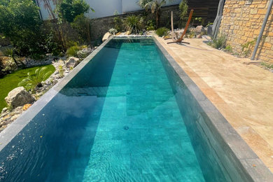 Cette photo montre une grande piscine moderne rectangle avec des pavés en pierre naturelle.