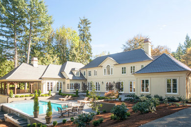 Large traditional yellow two-story stucco exterior home idea in Portland with a hip roof