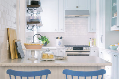 ジャクソンビルにあるトランジショナルスタイルのおしゃれなキッチン (エプロンフロントシンク、シェーカースタイル扉のキャビネット、青いキャビネット、珪岩カウンター、白いキッチンパネル、サブウェイタイルのキッチンパネル、シルバーの調理設備、無垢フローリング、茶色い床、白いキッチンカウンター) の写真