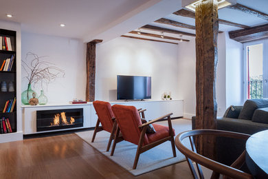 Modelo de salón para visitas abierto rural de tamaño medio con marco de chimenea de metal, paredes blancas, suelo de madera en tonos medios, chimenea lineal y pared multimedia