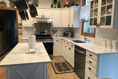 Inspiration for a mid-sized l-shaped eat-in kitchen in Cleveland with an undermount sink, raised-panel cabinets, white cabinets, quartz benchtops, multi-coloured splashback, ceramic splashback, stainless steel appliances, with island, beige floor and multi-coloured benchtop.