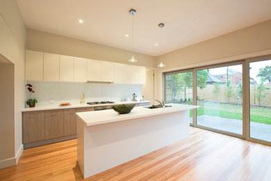 Photo of a small modern galley eat-in kitchen in Melbourne with an undermount sink, open cabinets, medium wood cabinets, quartz benchtops, white splashback, glass sheet splashback, stainless steel appliances, medium hardwood floors and with island.