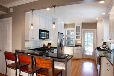 Inspiration for a mid-sized timeless u-shaped medium tone wood floor eat-in kitchen remodel in Baltimore with a double-bowl sink, recessed-panel cabinets, white cabinets, granite countertops, white backsplash, subway tile backsplash, stainless steel appliances and a peninsula