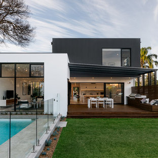 Exempel på ett modernt flerfärgat radhus, med två våningar, fiberplattor i betong, platt tak och tak i metall