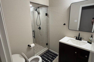 Example of a small minimalist ceramic tile, beige floor and single-sink alcove shower design in Austin with flat-panel cabinets, black cabinets, a bidet, beige walls, an integrated sink, marble countertops, a hinged shower door, white countertops and a niche