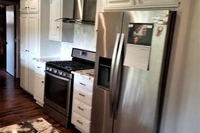 Kitchen - modern dark wood floor and brown floor kitchen idea in Oklahoma City with shaker cabinets, white cabinets, granite countertops, white backsplash, marble backsplash, white appliances, an island and an undermount sink