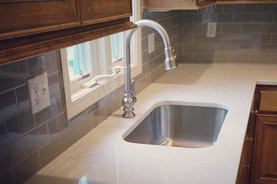 Eat-in kitchen - mid-sized traditional u-shaped medium tone wood floor and brown floor eat-in kitchen idea in Kansas City with an undermount sink, raised-panel cabinets, medium tone wood cabinets, laminate countertops, beige backsplash, subway tile backsplash, stainless steel appliances and an island