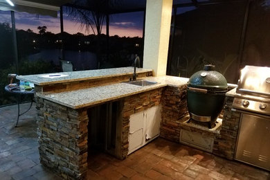 Inspiration for a mid-sized transitional backyard concrete paver patio kitchen remodel in Tampa with a roof extension