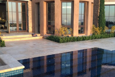 Example of a classic backyard stone and custom-shaped infinity pool design in Orange County