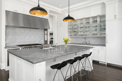 Open concept kitchen - large transitional u-shaped dark wood floor open concept kitchen idea in Chicago with a farmhouse sink, recessed-panel cabinets, white cabinets, quartzite countertops, white backsplash, mosaic tile backsplash, white appliances and an island
