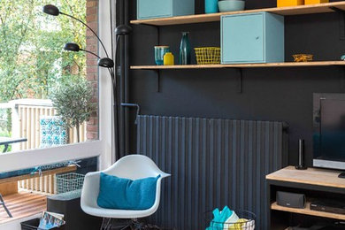 Exemple d'un grand salon tendance ouvert avec un mur noir, un sol en bois brun et un téléviseur dissimulé.