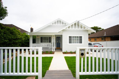 Modelo de fachada de casa blanca y blanca de tamaño medio de una planta con revestimiento de madera, tejado a dos aguas y tejado de metal