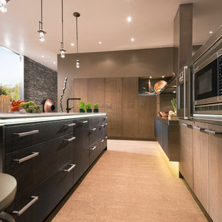 Exemple d'une grande arrière-cuisine tendance en L avec un placard à porte plane, des portes de placard en bois brun, un plan de travail en verre, une crédence noire, un électroménager en acier inoxydable, un sol en bois clair et un îlot central.