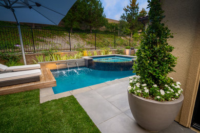 Design ideas for a small modern drought-tolerant and partial sun backyard water fountain landscape in Orange County with decking.