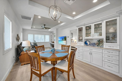 Great room - mid-sized coastal light wood floor, beige floor and tray ceiling great room idea in Miami with white walls