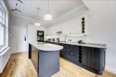 Foto på ett mellanstort funkis kök, med granitbänkskiva, vitt stänkskydd, stänkskydd i keramik, svarta vitvaror, vinylgolv och brunt golv