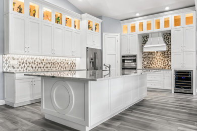 Example of a large trendy l-shaped ceramic tile, multicolored floor and vaulted ceiling eat-in kitchen design in Other with a drop-in sink, shaker cabinets, white cabinets, quartzite countertops, metallic backsplash, metal backsplash, stainless steel appliances, an island and gray countertops