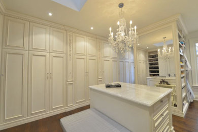 Walk-in closet - large traditional gender-neutral dark wood floor walk-in closet idea in New York with recessed-panel cabinets and white cabinets