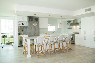 Kitchen - transitional u-shaped light wood floor and beige floor kitchen idea in Miami with a farmhouse sink, shaker cabinets, white cabinets, white backsplash, paneled appliances, an island and white countertops