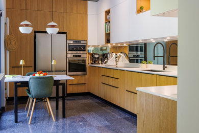 パリにあるコンテンポラリースタイルのおしゃれなキッチン (一体型シンク、フラットパネル扉のキャビネット、淡色木目調キャビネット、珪岩カウンター、シルバーの調理設備、大理石の床、青い床、白いキッチンカウンター) の写真