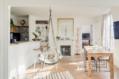 Inspiration for a contemporary kitchen/dining combo in Paris with white walls, light hardwood floors and a standard fireplace.