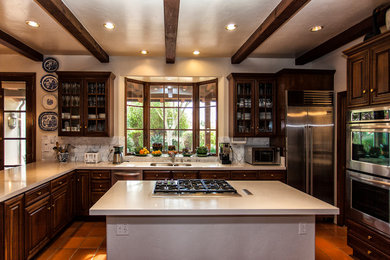 Huge elegant u-shaped terra-cotta tile open concept kitchen photo in Orange County with an undermount sink, raised-panel cabinets, dark wood cabinets, quartzite countertops, white backsplash, stone tile backsplash, stainless steel appliances and two islands
